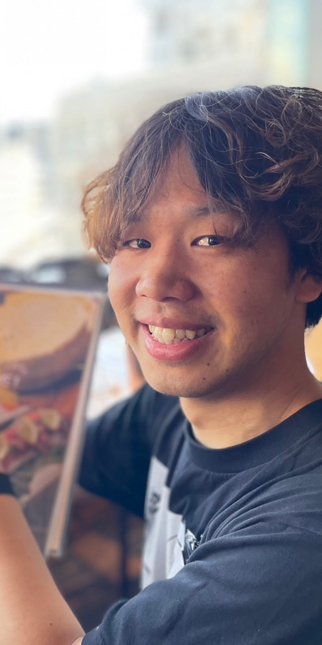 西山さんが笑顔でメニューをこちらに見せている様子