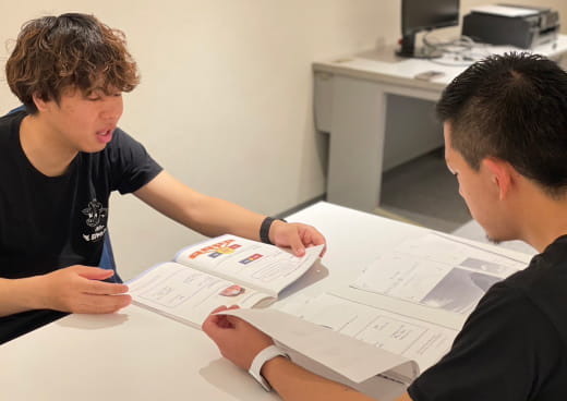 会議室で男性社員２人が座りながら、向かい合って会議をしている様子